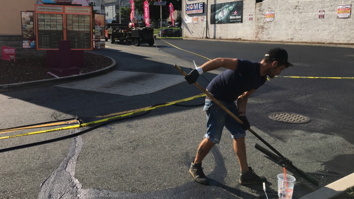 Drive Sealcoating crew applying sealer with a squeegee